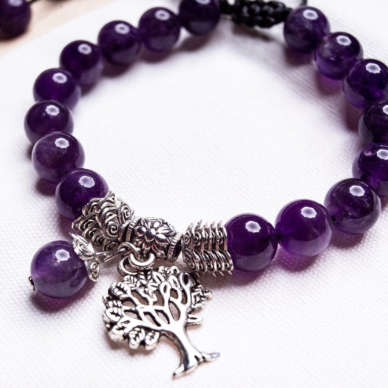 Amethyst Tree of Life Bracelet with purple beads, silver-colored spacers and a tree charm on a light background.
