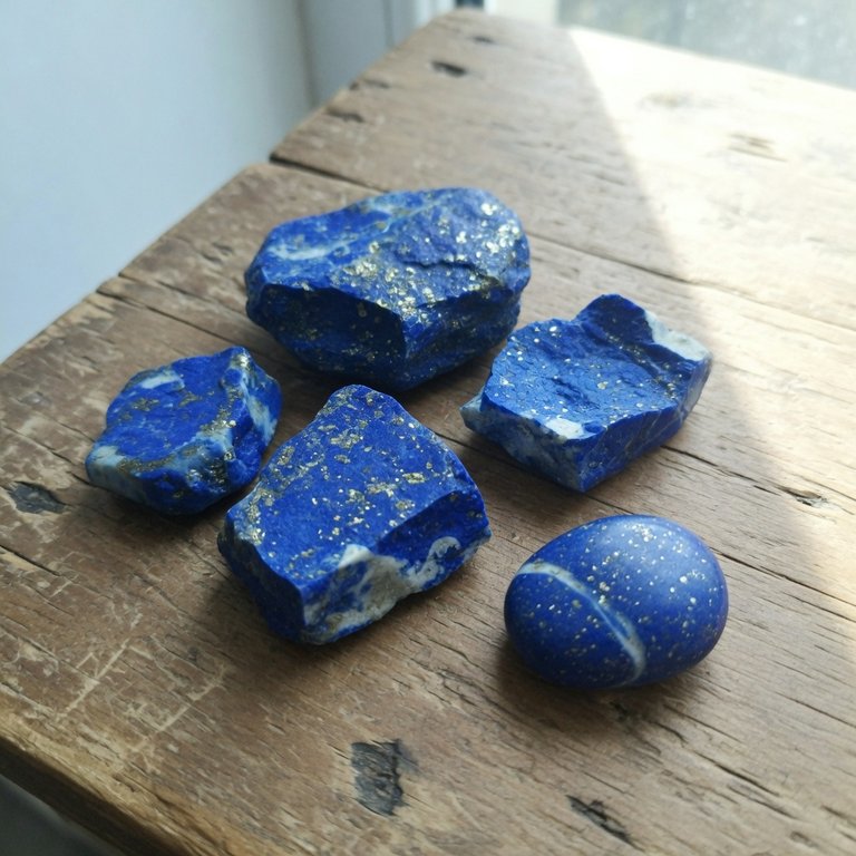 Rough lapis lazuli stones on a wooden table in window light