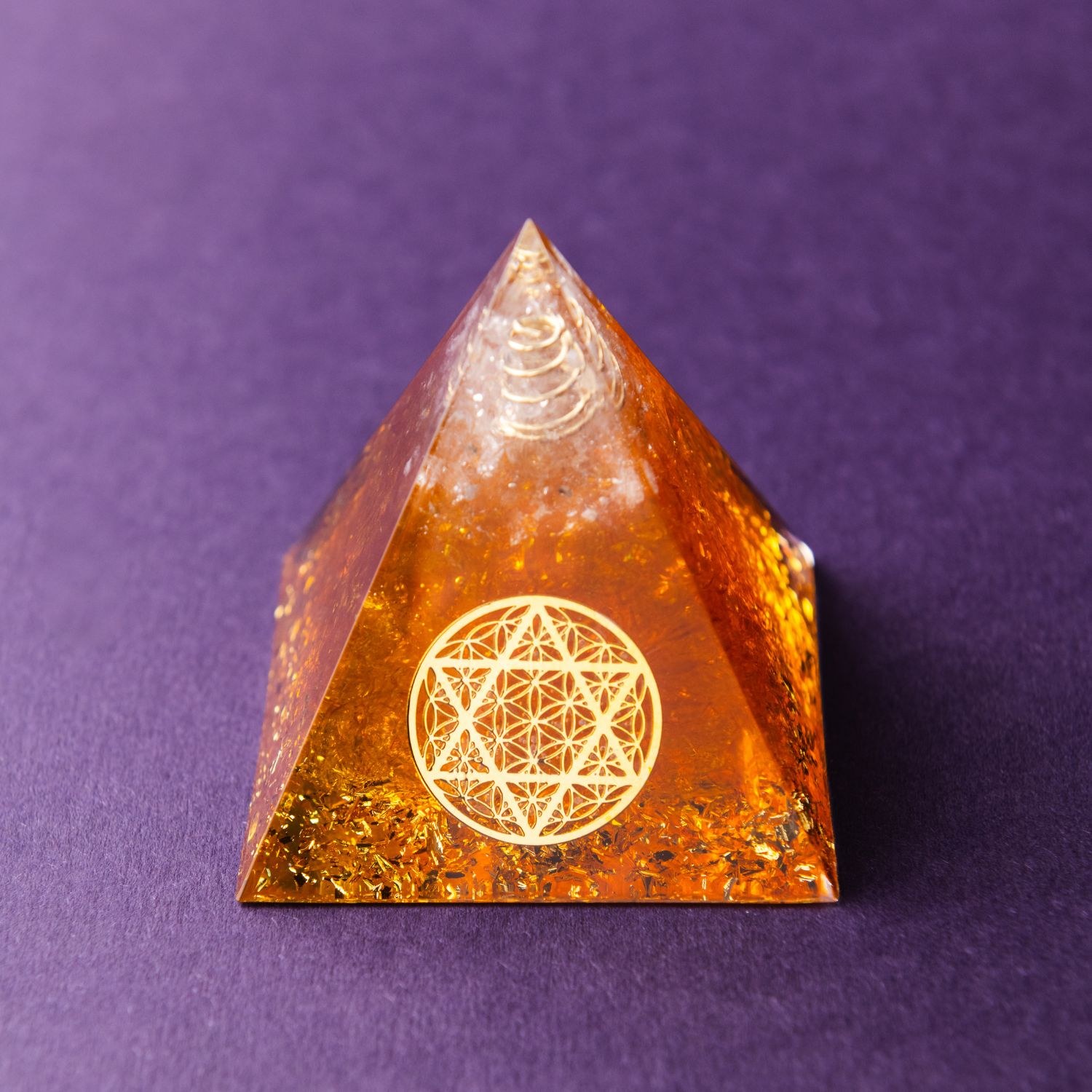 Citrine Orgonite Pyramid of Manifestation on a dark surface
